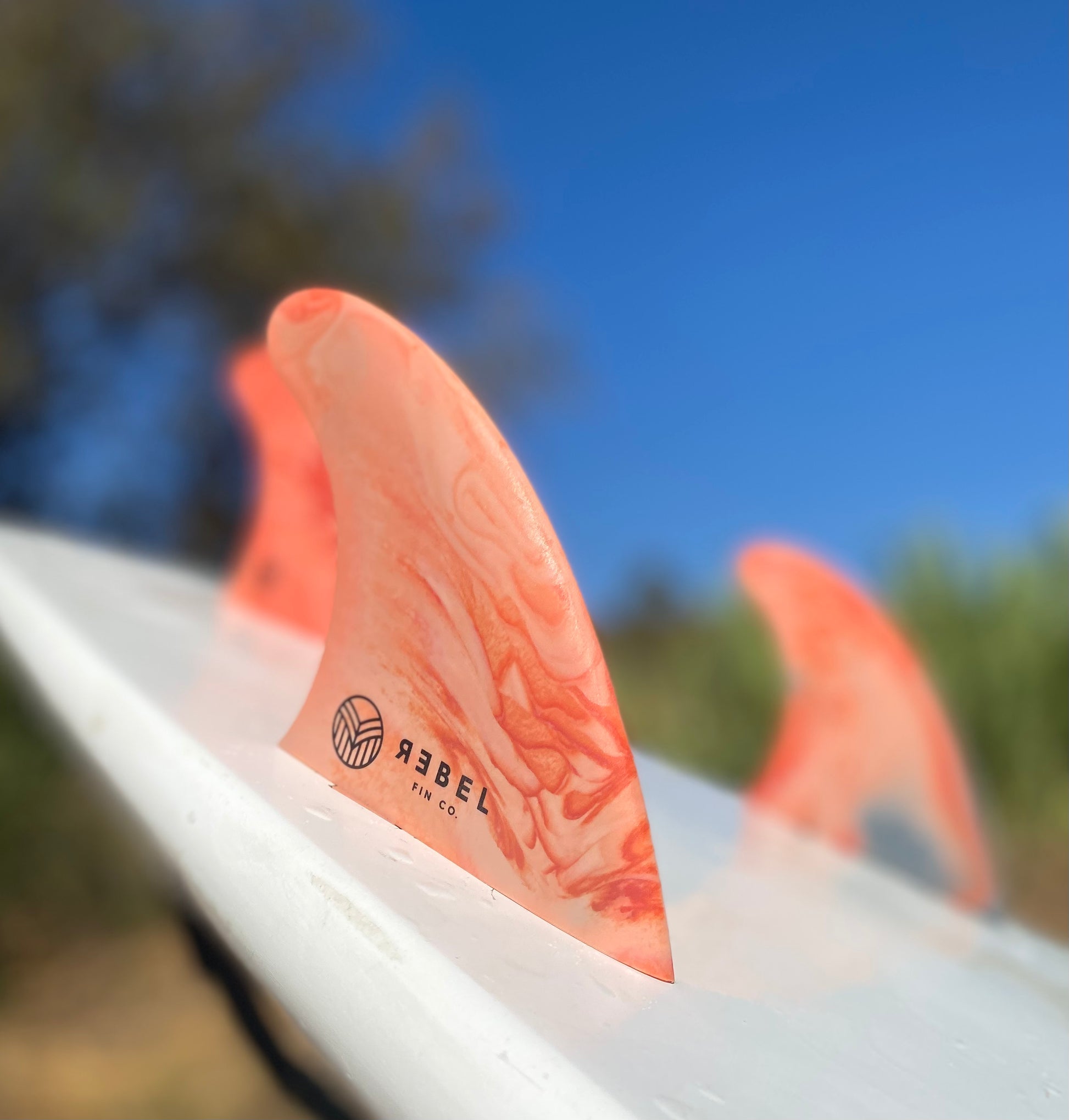 A set of Rebel thruster surf fins shown attached to a surfboard.